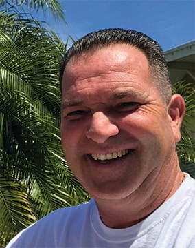 Photo of Jimmy McQuade, with Florida palm trees behind him.